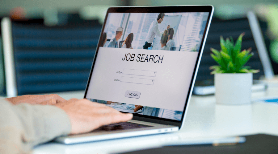 Hands typing job search on laptop